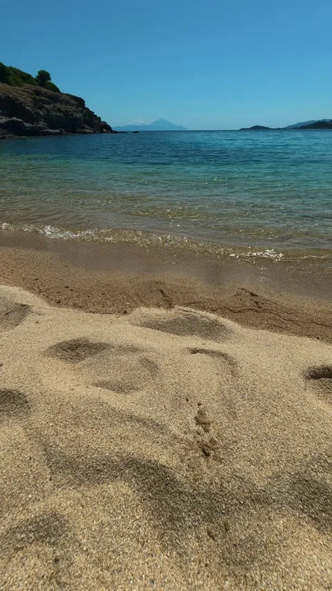 Footprints mark path where gentle waves retreat. Trani Ammouda, Greece. Vertical Stock Footage 339629475