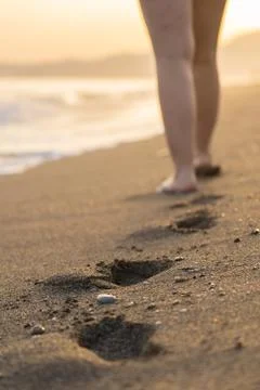 Footprints on the sand at the beach next to the waves Stock Photos