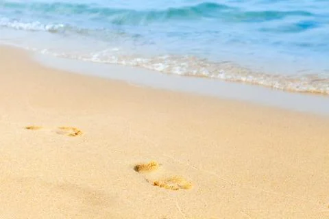 Footprints in the sand on a beach by the sea. Summer vacation concept. Stock Photos