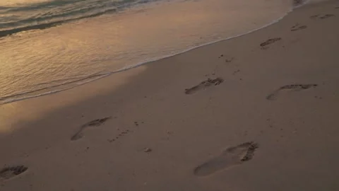 Footprints in sand washed by wave Stockbeeldmateriaal 347990404