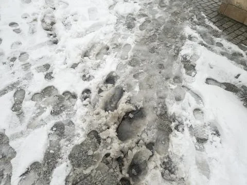 Footprints in the snow create a unique pattern on the icy pavement, illustrating 스톡 사진