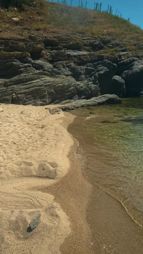 Footprints trace path along sunlit beach. Trani Ammouda, Greece. Vertical Stock Footage 339629388