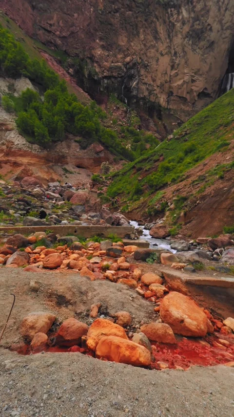 Footsteps lead through striking orange rocks towards a gentle stream, surrounded Stock-Footage 312462777