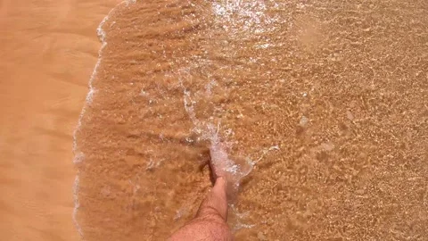 Footsteps in shallow water, capturing the gentle waves lapping against the sandy Stock-Footage 317677576