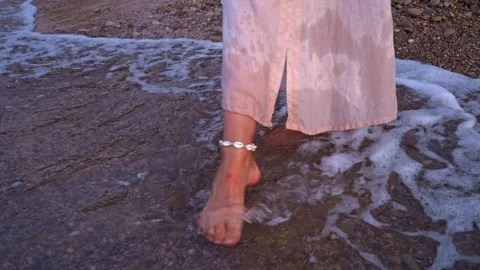Footsteps by the shore with waves at sunset Stock Footage 346016723