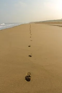 Footsteps on a smooth deserted beach Stock Photos