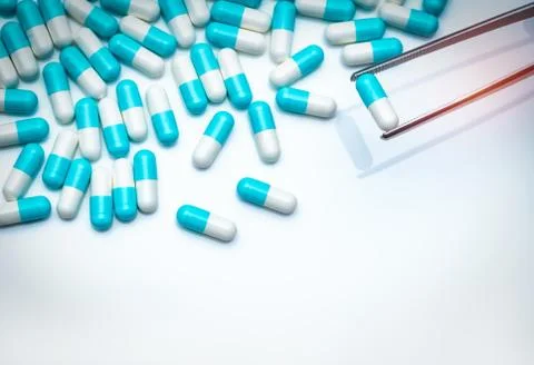 Forceps pick white-blue capsule from group of capsule pills. Drugs choose. An 스톡 사진