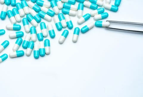 Forceps pick white-blue capsule from group of capsule pills. Drugs choose. An Stock-Fotos