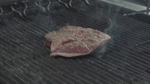 Forceps turning over the piece of meat on a frying pan Stock Footage 80907333