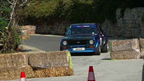 Ford Escort Mark II and orange VW Beetle slow‑motion passes through chicane on Stock Footage 324934883