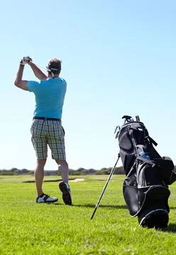 Fore. Rearview of a mature male golfer playing on shot on the golf course. Stock Photos