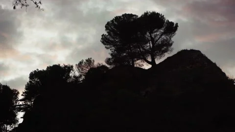 A foreboding clouded sunset sky with the silhouette of trees on a hill. Stock Footage 168728593