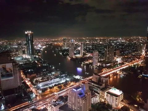 The foreground features a river, while the city skyline can be seen at night Stock Photos