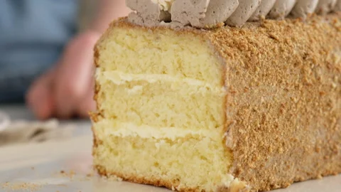 Foreground. Female hand taking a piece of sponge cake with chocolate cream and Video stock 146480202