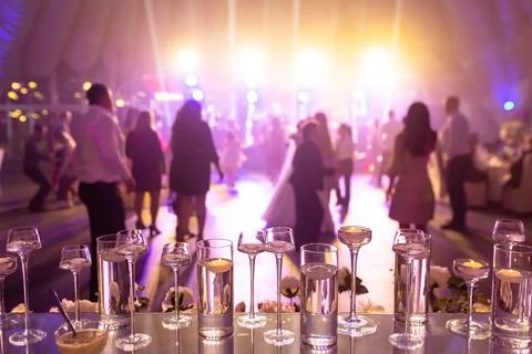 Foreground focus vases on glass table with dancing people at wedding Stock Photos