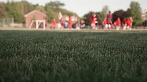 Foreground grass with soccer game blurred in background REC 709 6K 29.97p Stockbeeldmateriaal 197415064