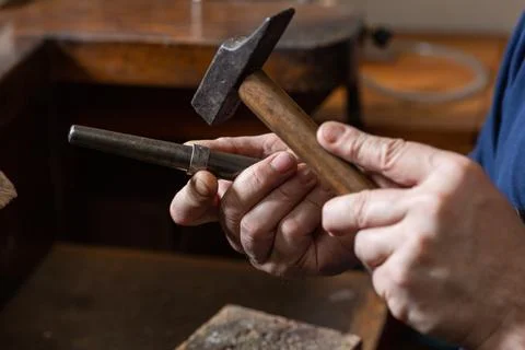 Foreground, hammer hammering a silver ring to shape it in a jewelry workshop. Stock Photos