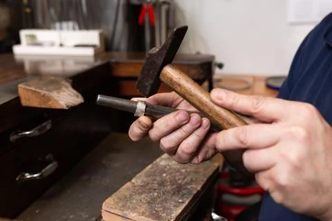 Foreground, hammer hammering a silver ring to shape it in a jewelry workshop. Stock Photos