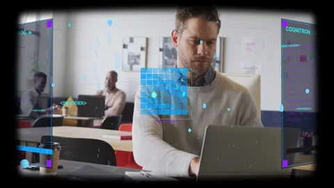 Foreground man typing on laptop at communal desk, activating holographic panels Stock Footage 332937334