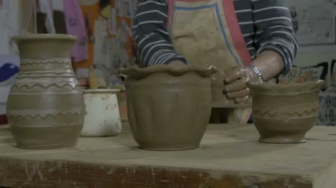 In foreground products of clay,in background man making vase, pottery, close up. Stock Footage 57636445