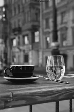 In the foreground, on the table, is a cup of coffee with and a glass of water Stock Photos