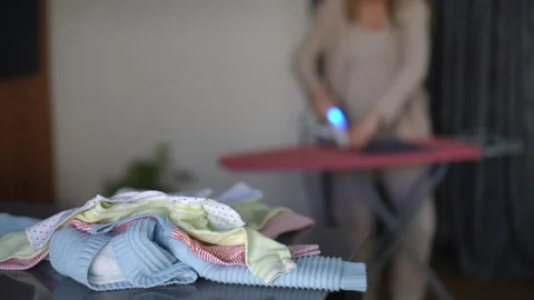 In the foreground there is a stack of baby clothes on the table. In the Stock Footage 273167836