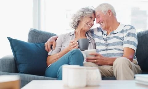 Forehead, touch and old couple with drink on sofa for bonding, commitment and Stock Photos