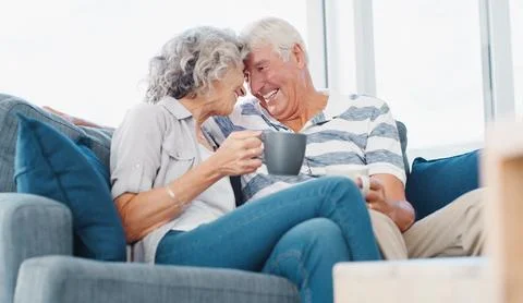 Forehead, touch and old couple with coffee on sofa for bonding, commitment and Stock Photos