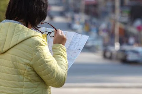 Foreign female model looking on printed paper map in search of fastest direct Stock Photos