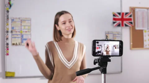 Foreign language tutor filming video on phone in classroom 動画素材 201596896