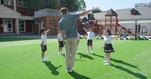 Foreign teacher and students exercising in kindergarten playground,4K Stock Footage 146827931