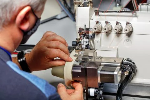 The foreman adjusts the correct operation of a modern sewing machine. Stock Photos