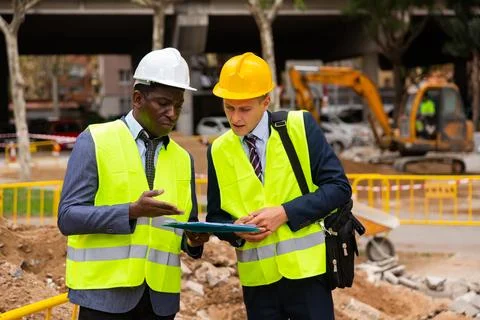 Foreman and engineer discussing about road paving project documentation Stock Photos