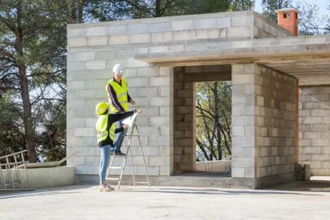 Foreman and his young apprentice on a construction site visit, house Stock Photos