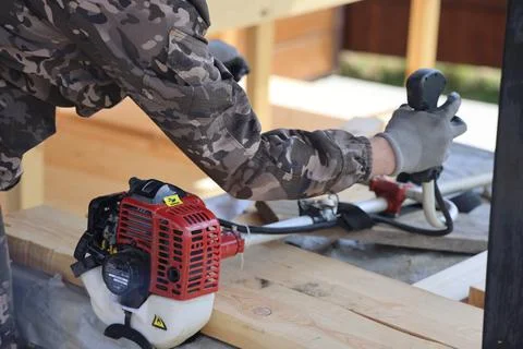 The foreman checks the work of the gasoline trimmer after winter storage, bac Stock Photos