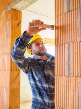 Foreman with construction plan checking construction work with pocket rule Stock Photos