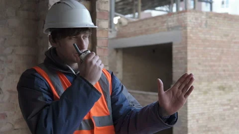The foreman at the construction site controls the process using a walkie-talkie. Stock Footage 157492888