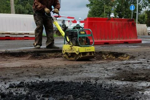 The foreman of the construction team works with a vibrating platform plate, t Stock Photos