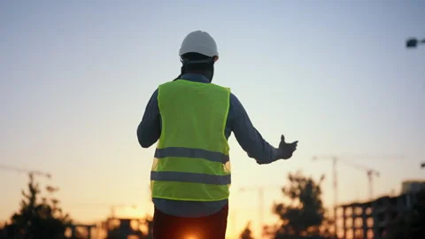 Foreman discussing building process, back view of man against construction site Stock Footage 318343430
