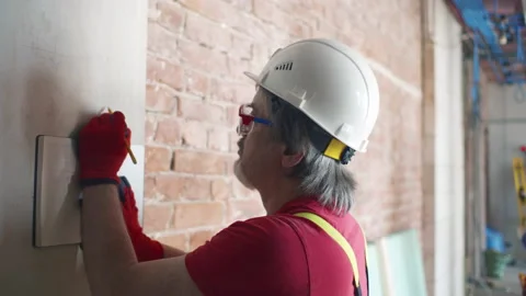 Foreman drawing on wall making calculation at construction site. Realtime Video stock 167449220