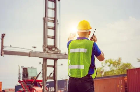 Foreman in hardhat talks on two-way radio control loading containers box Фото