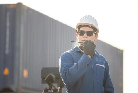 Foreman in hardhat talks on two-way radio control loading containers box Photos