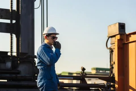 Foreman in hardhat talks on two-way radio control loading containers box Фото