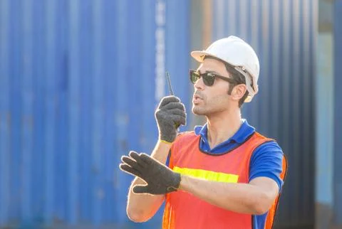 Foreman in hardhat talks on two-way radio control loading containers box Фото