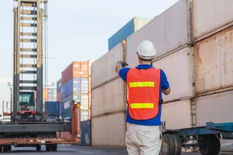 Foreman in hardhat talks on two-way radio control loading containers box Photos