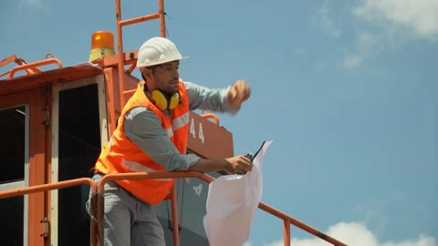Foreman holding blueprint talking on the walkie-talkie control loading Contai Stock Footage 145207610