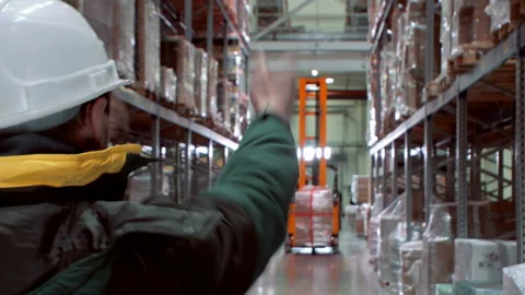 The foreman leads the work of the professional driver operates forklift truck  Stock Footage 105990545