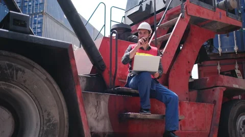 Foreman or cargo container worker man sit on side of crane truck and use laptop Stock Footage 146712764