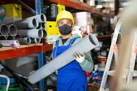Foreman in protective mask looking for PVC pipes in building hypermarket Fotos de archivo