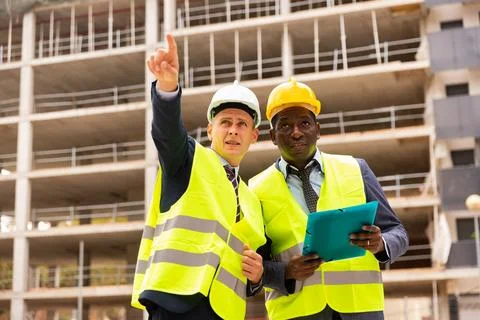 Foreman showing builder something at the construction site by pointing hand Stock Photos